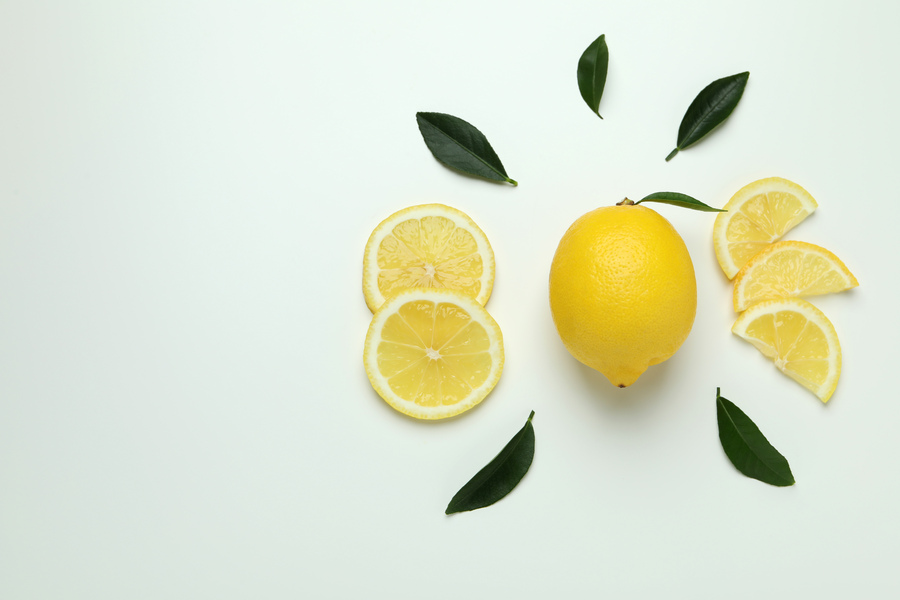 Une citron jaune entourée par quelques rondelles et des feuilles vertes