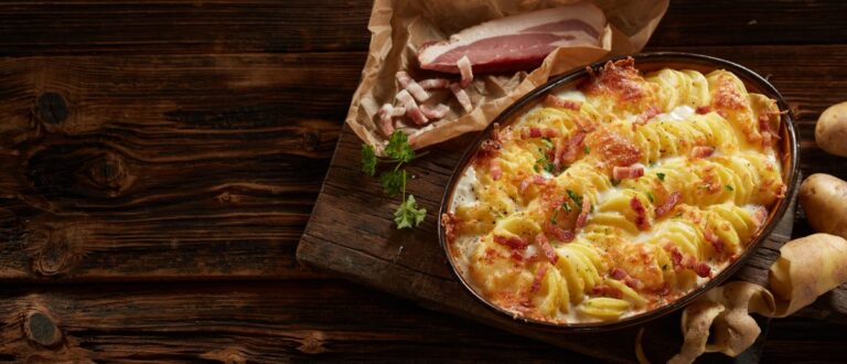 Pommes de terre coupées, lardons dorés et oignons fondus répartis dans un plat avant cuisson