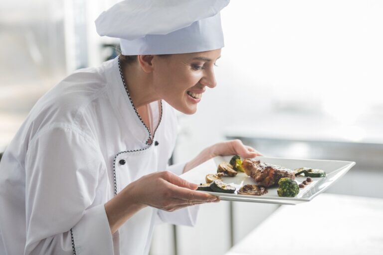 Un chef reniflant un steak cuit sur une assiette
