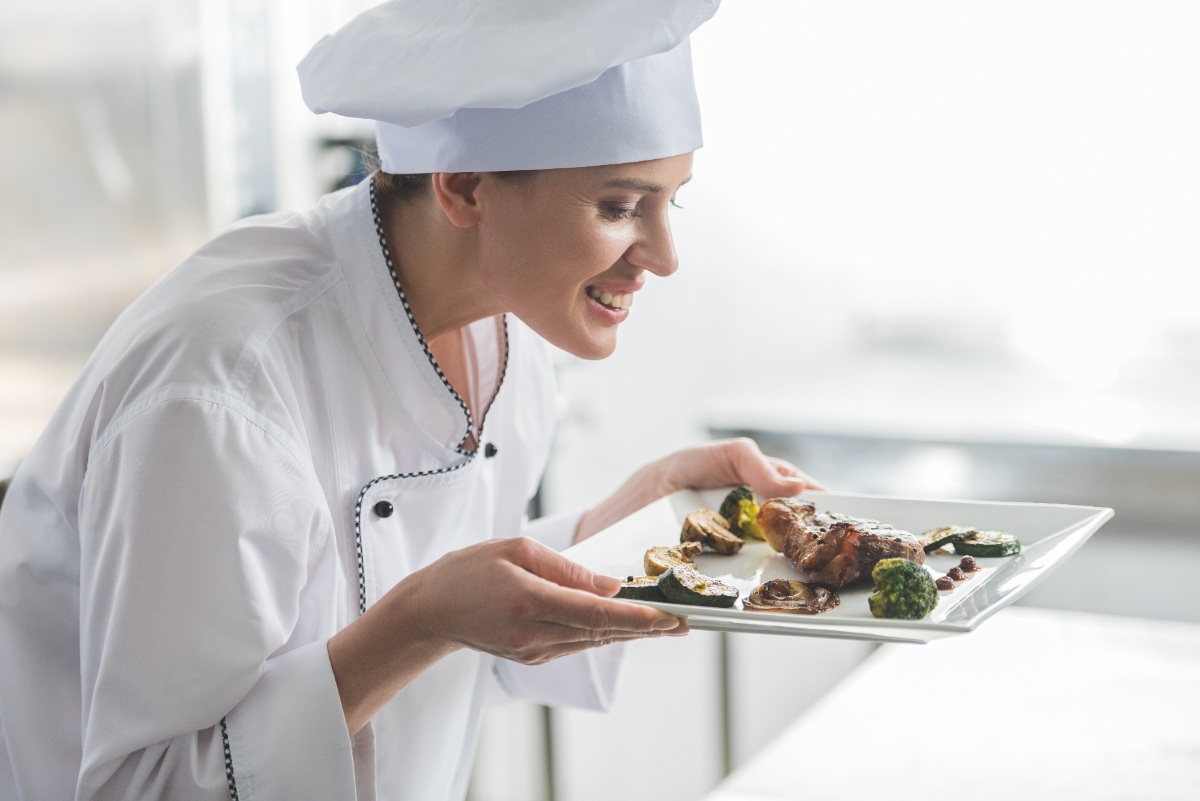 Un chef reniflant un steak cuit sur une assiette