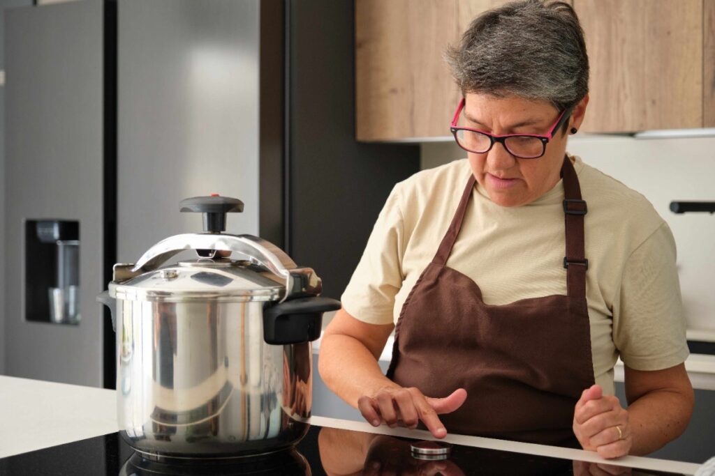 Une femme âgée dans une cuisine en utilisant une cocotte-minute SEB en aluminium