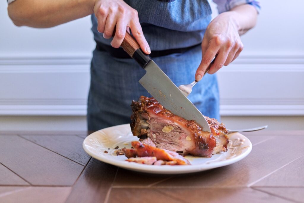 Une personne utilisant du couteau pour trancher un confit de porc