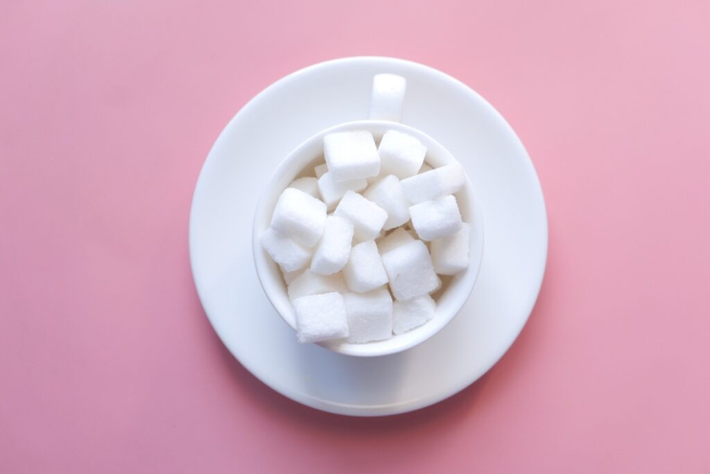 Un bol blanc rempli de morceau de sucre, posé sur une assiette