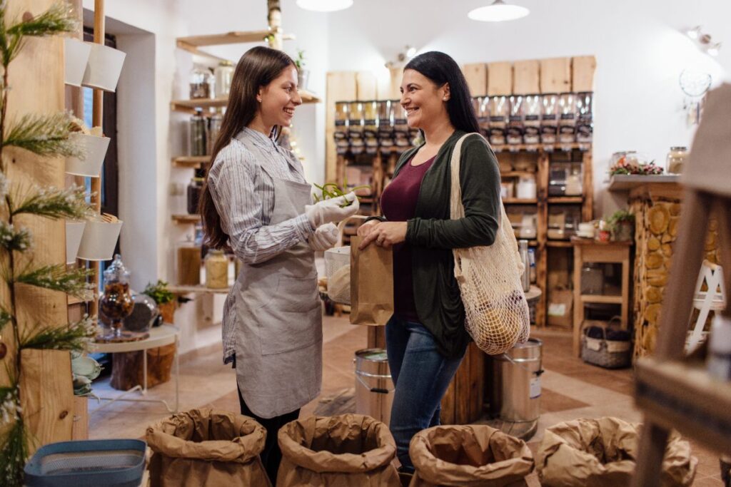 Une commerçante souriante qui aide une cliente dans une boutique 