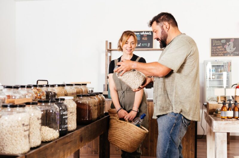 Un couple qui sélectionne des haricots dans des bacs dans une épicerie écologique