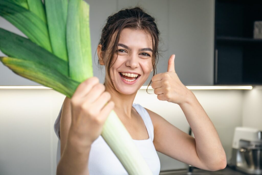 Une femme heureuse qui tient un poireau