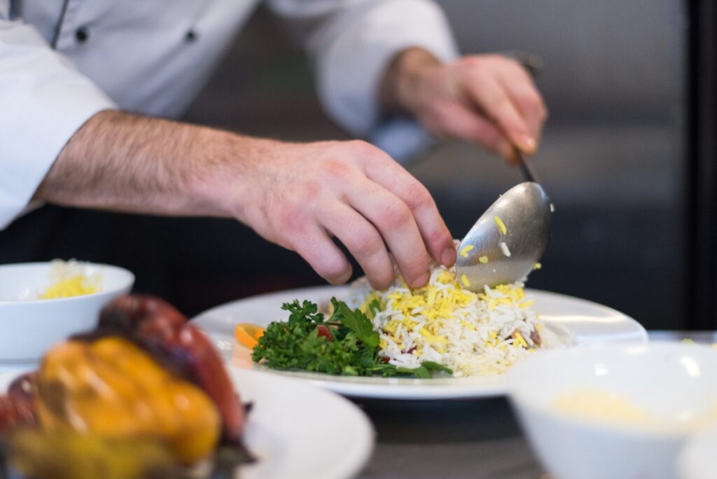 Des mains d'un chef qui servent du risotto aux légumes