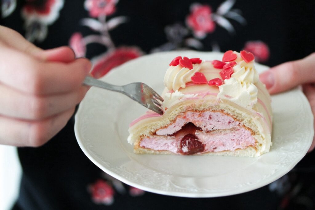 Une personne avec une fourchette et prend du gâteau aux biscuits roses de Reims