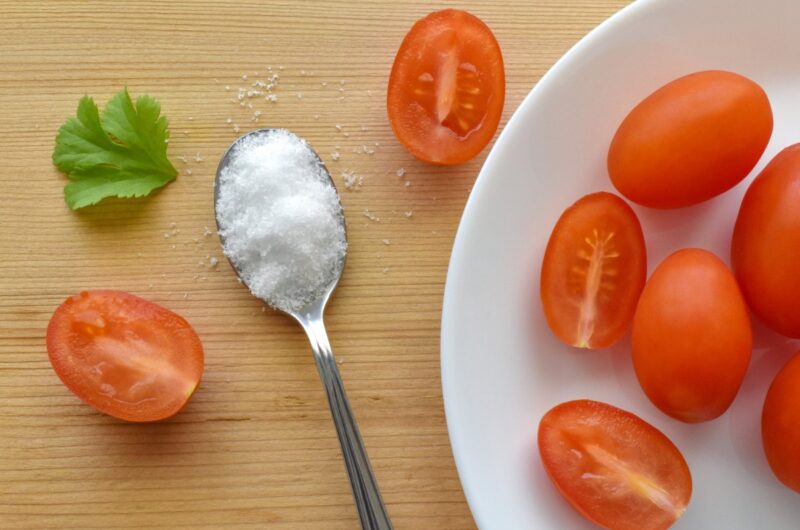 Des tomates sur une assiette et une cuillère de sucre