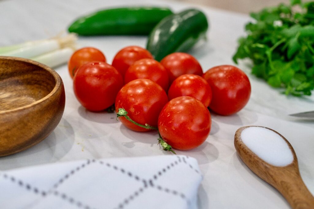 Des tomates, poivrons et une cuillère de sucre sur la table