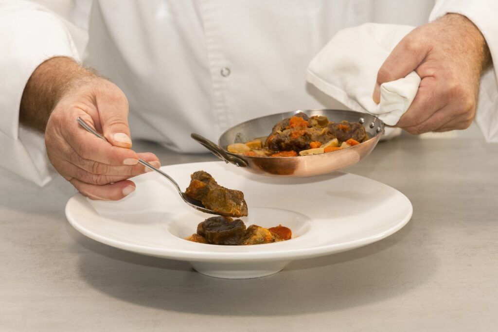 Un chef préparant une assiette de boeuf bourguignon