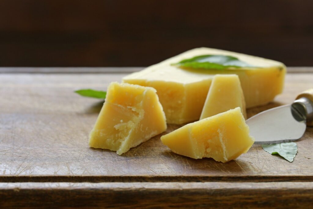 Des morceaux de fromage avec un couteau sur une planche à découper