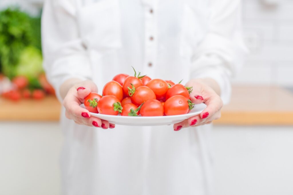 Une femme tenant une assiette de tomates fraîches