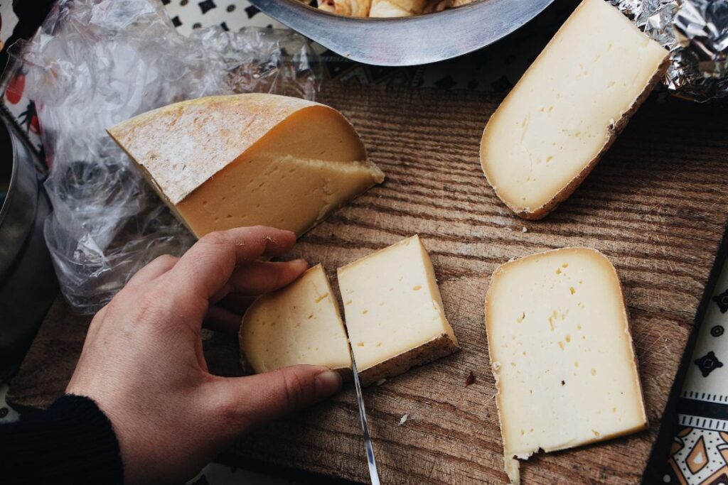 Main qui coupe du fromage avec un couteau