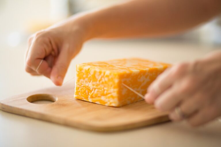Mains coupant du fromage sur une planche à découpe