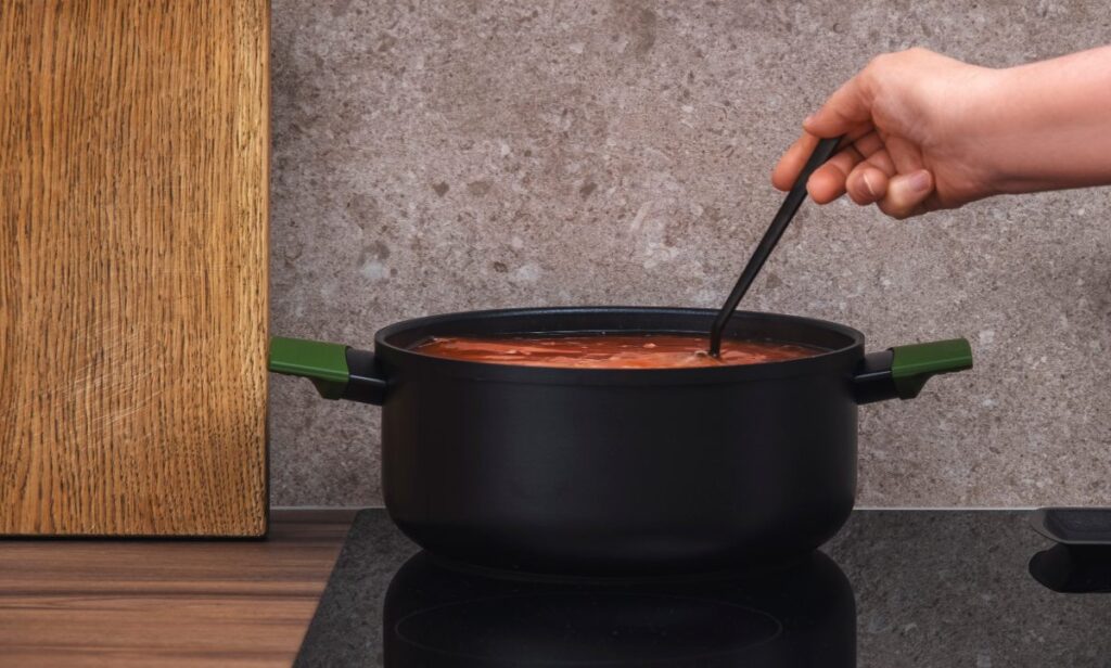 Une personne mélangeant de la soupe dans une cocotte