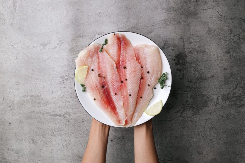 Une personne tenant une assiette de poisson cru