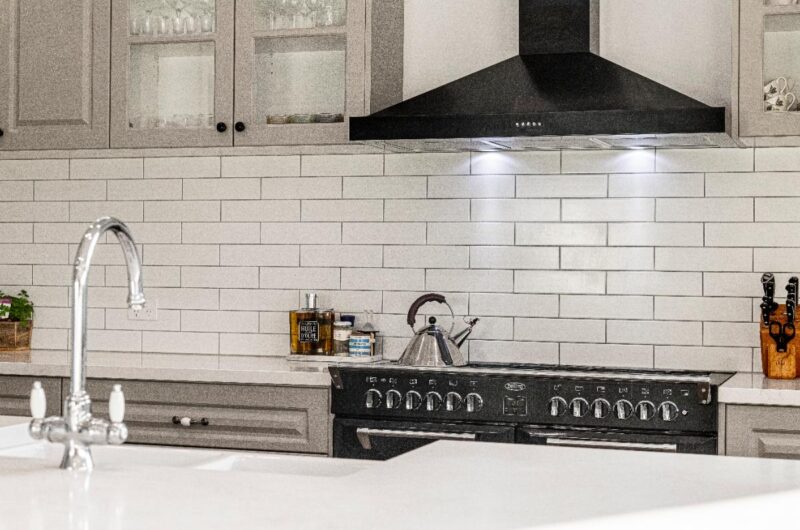 Une cuisine moderne avec du carrelage blanc et de hotte noire