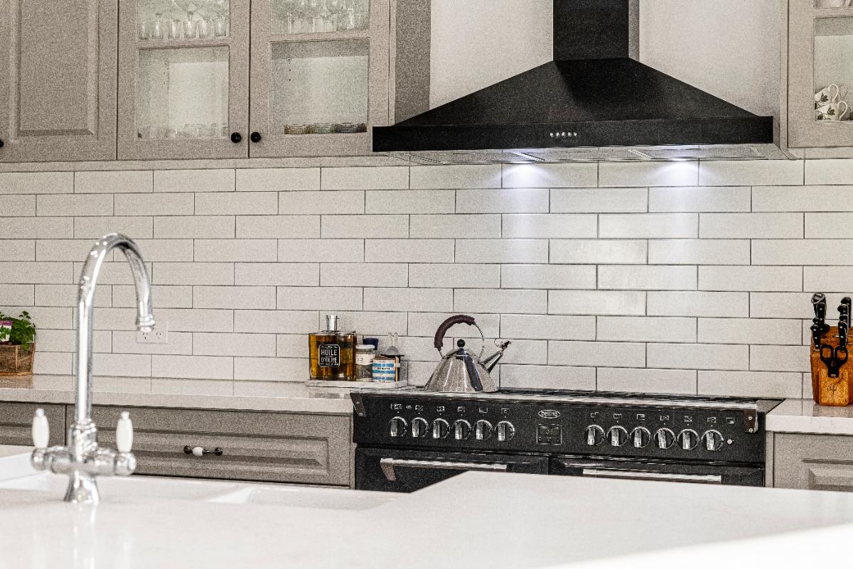 Une cuisine moderne avec du carrelage blanc et de hotte noire