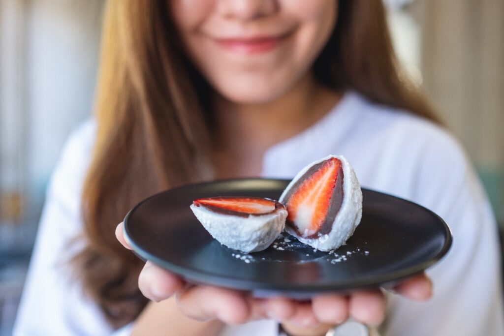 Une femme tenant un assiette avec du mochi à la fraise