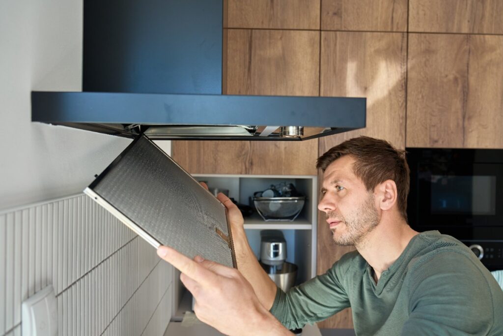 Un homme installant une hotte dans la cuisine