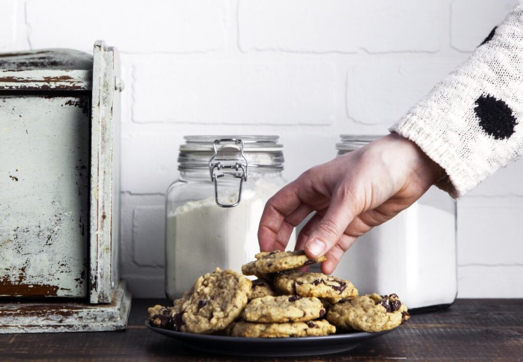 Main prenant du cookies aux pépites de chocolat