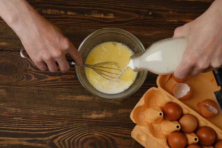 Une personne qui verse du lait dans un bol avec des oeufs