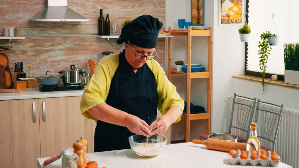 Une grand-mère mélangeant avec soin les oeufs et la farine pour réussir le baba au rhum